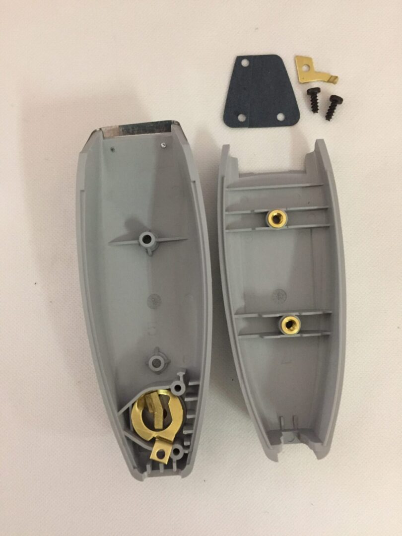 A pair of grey plastic parts with yellow hardware.