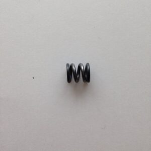 A black metal coil sitting on top of a white wall.