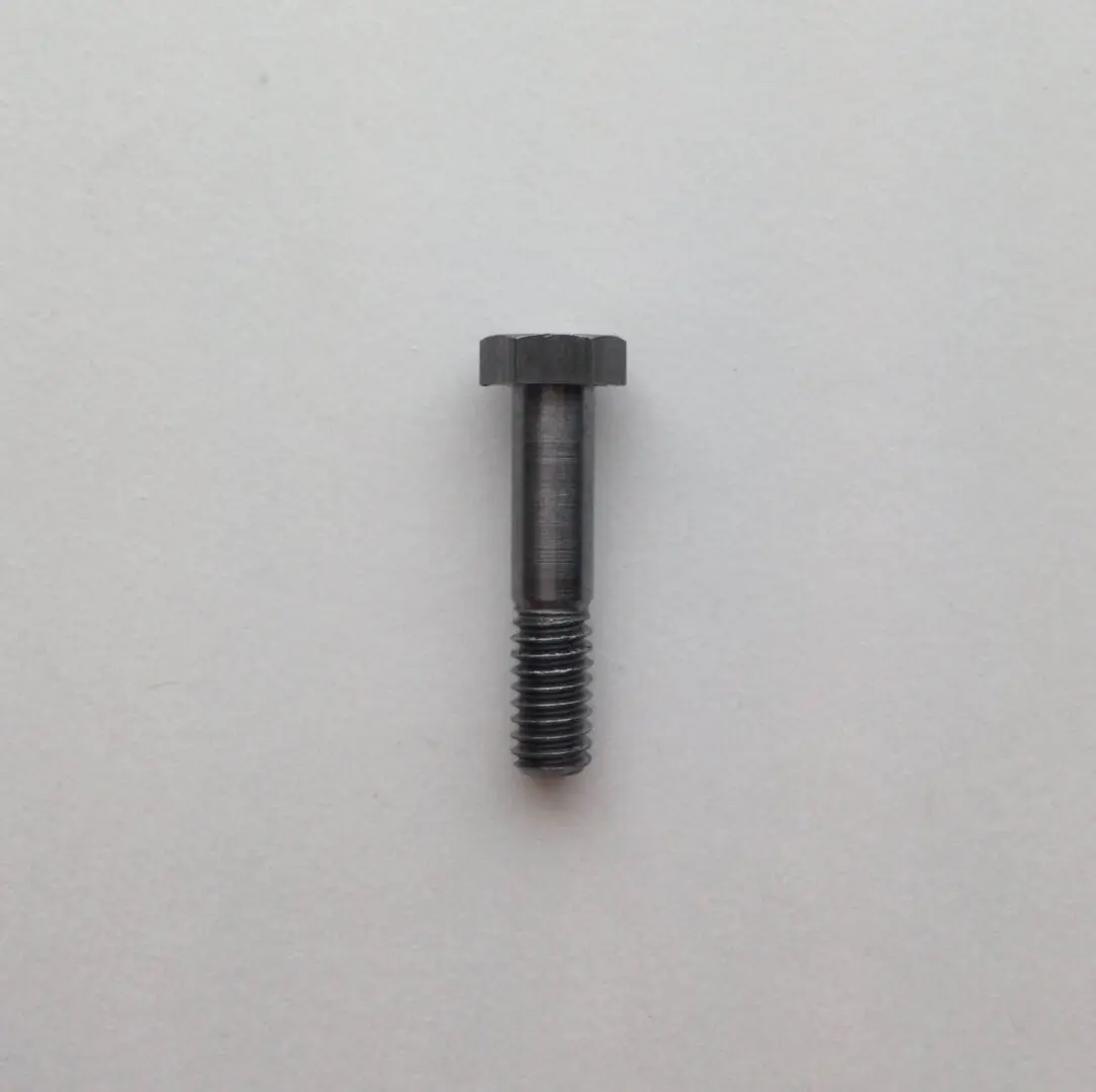 A black metal screw sitting on top of a white table.