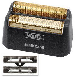 A black and gold wahl razor blade holder next to the blade.